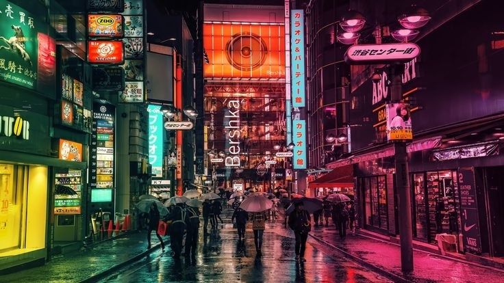 Regnig nattgata med neonljus, skyltar och människor under paraplyer